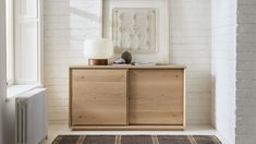 a white brick wall in a room with a wooden cabinet and rug on the floor