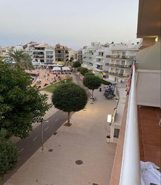 an empty street in the middle of a city with lots of trees and people walking on it