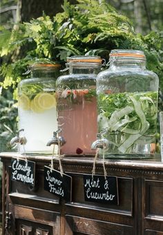 three mason jars filled with water and herbs on top of a table in the woods