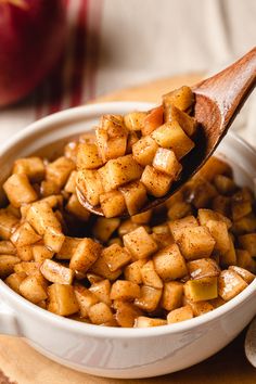 a spoon full of cooked apples in a white bowl