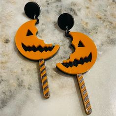 two orange and black halloween earrings with jack - o'- lantern faces on them