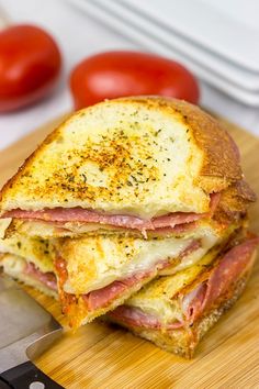 a ham and cheese sandwich cut in half on a cutting board with a knife next to it