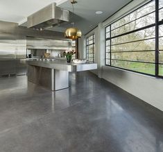 an empty kitchen with stainless steel appliances and large windows