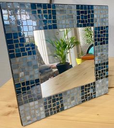 a mirror that is sitting on top of a wooden table next to a potted plant