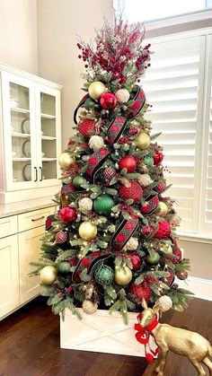 a decorated christmas tree in a living room with red and green ornaments on the top