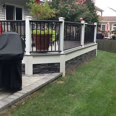 a bbq grill sitting on top of a wooden deck next to a fenced in yard