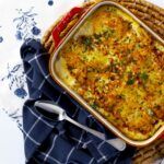 a casserole dish is sitting on a blue and white cloth next to silverware