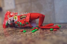 a candy bar with green and red candies spilling out of it on top of a counter