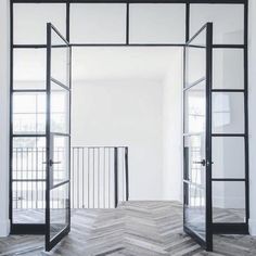 an open room with wooden floors and glass doors on the door, in front of a white wall