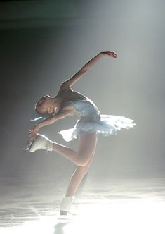 a young ballerina is performing on the ice rink in front of bright spotlights