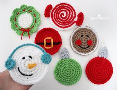 crocheted christmas ornaments are displayed on a white surface with a person's hand