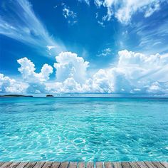 a wooden dock in the middle of an ocean with blue sky and clouds above it