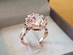 a pink diamond ring sitting in a box