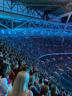 a large crowd is sitting in the stands at a sporting event with bright blue lights