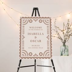 an easel with a welcome sign on it in front of a string of lights