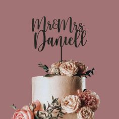 a wedding cake with flowers on top and the words mr and mrs danielle written in cursive