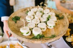 several appetizers are arranged on a wooden platter with toothpicks in them