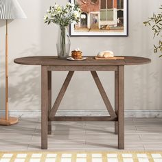 a wooden table with flowers in a vase on top and a lamp next to it