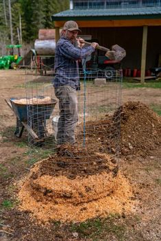 a man standing next to a pile of dirt in front of a fenced off area