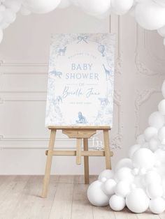 a baby shower sign sitting on top of a easel in front of white balloons