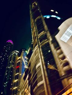 the city is lit up at night with skyscrapers in the foreground and buildings on either side