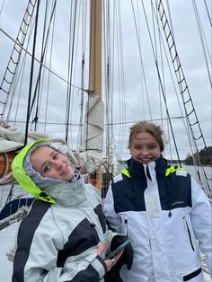 two women standing next to each other on a boat