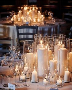 a table topped with lots of candles and glasses filled with wineglasses next to each other