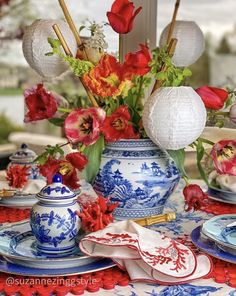 a blue and white vase filled with flowers on top of a table covered in plates