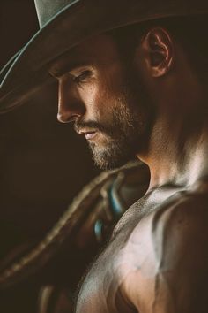 a man wearing a cowboy hat with his arm around the neck and shoulder, looking off into the distance