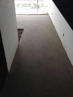 an empty room with concrete floors and white walls, looking out onto a parking lot