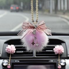 a car dashboard decoration with pink and silver decorations on it's dash board, hanging from the ceiling