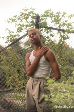 a man standing in front of a chain link fence with his hands on his chest