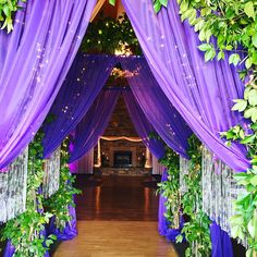 an archway decorated with purple drapes and greenery