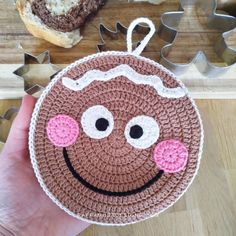 a crocheted bag with a smiling face on it and some cookies in the background