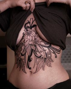 a woman's stomach with tattoos on it and flowers in the bottom part of her belly