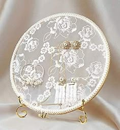 a white doily with flowers on it and two gold hooks in front of it