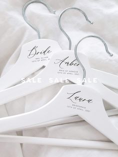 three white wooden hangers with names on them