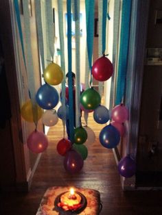 a birthday cake sitting on top of a wooden floor next to balloons and streamers