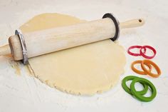 an uncooked pizza dough on a table next to some scissors and rolling pin