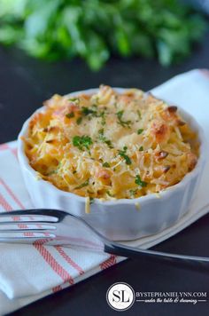 a white bowl filled with pasta and cheese on top of a napkin next to a fork