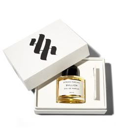 a bottle of perfume sitting in a white box next to a black and gold object