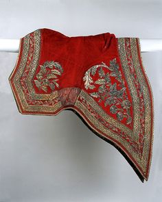 a red and gold scarf hanging on a white wall