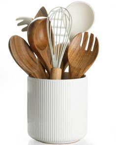 wooden utensils and spoons are in a white cup on a white surface