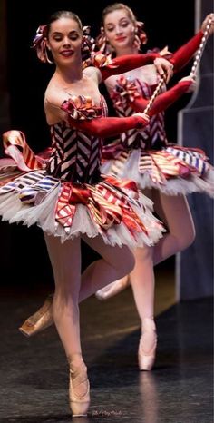 two ballerinas dressed in red and white tutus, one holding a cane