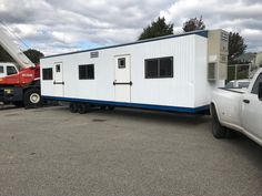 a white truck is parked next to a tiny house on the back of a trailer