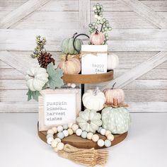 three tiered trays filled with decorative pumpkins and other fall decorations on top of a table