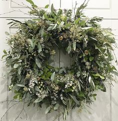 a wreath hanging on the side of a door with green leaves and berries around it