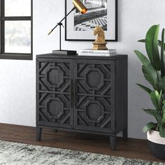 a black cabinet with a lamp on top next to a potted plant