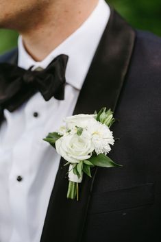 a man in a tuxedo wearing a boutonniere with white flowers