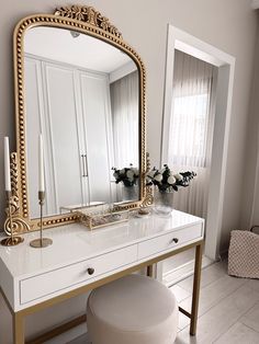 a white vanity with a gold mirror on it